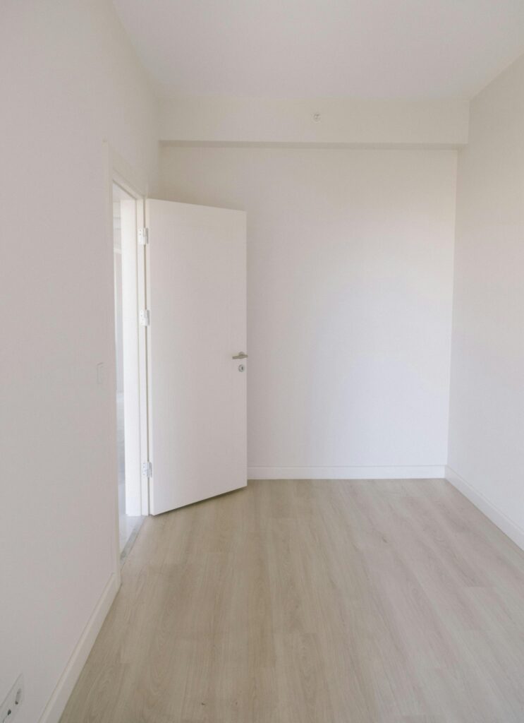 A bright, empty minimalist room with white walls and wooden flooring in Istanbul.